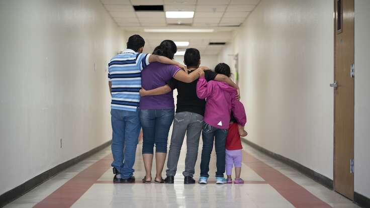 A family of 4 have their backs turned and arms around each other