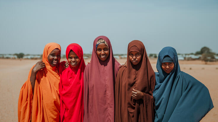 Five girls who are part of the IRC's Girl Shine program -- Ampia, Asha, Hibo, Shamsa, and Nurta -- stand together for a photo in a dry landscape in Ethiopia.