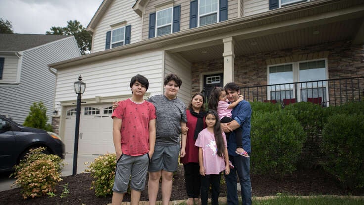 Photo of former Afghan refugee Noori standing outside his house with his family