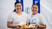 Two women smiling at the camera and holding a plate of food