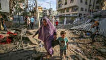A mother and child walk through the destruction caused by Israeli air strikes in Gaza City.
