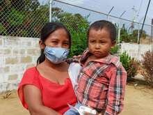 Eine Mutter hält ihr Kind im Freien. Die beiden posieren für ein gemeinsames Foto.