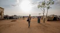 An IRC staff walks towards a camp for displaced people in South Sudan.