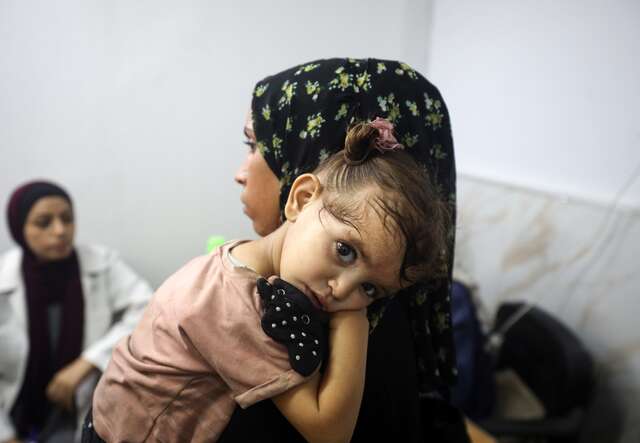 A young Palestinian girl clings to her mother.